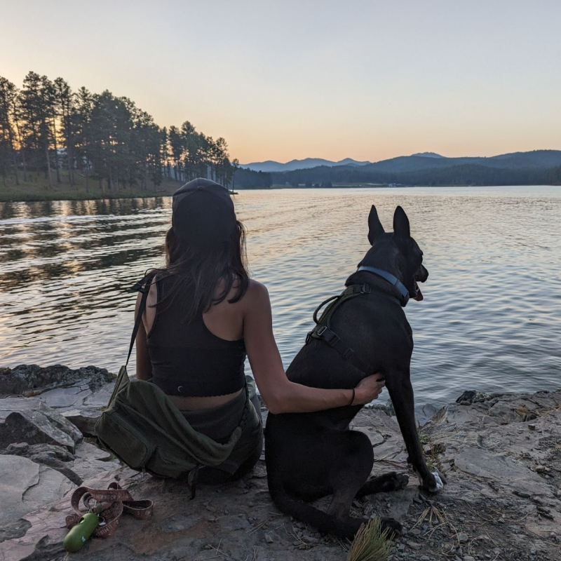 Cortney and her dog, Lola, sitting by a mountain lake at sunset